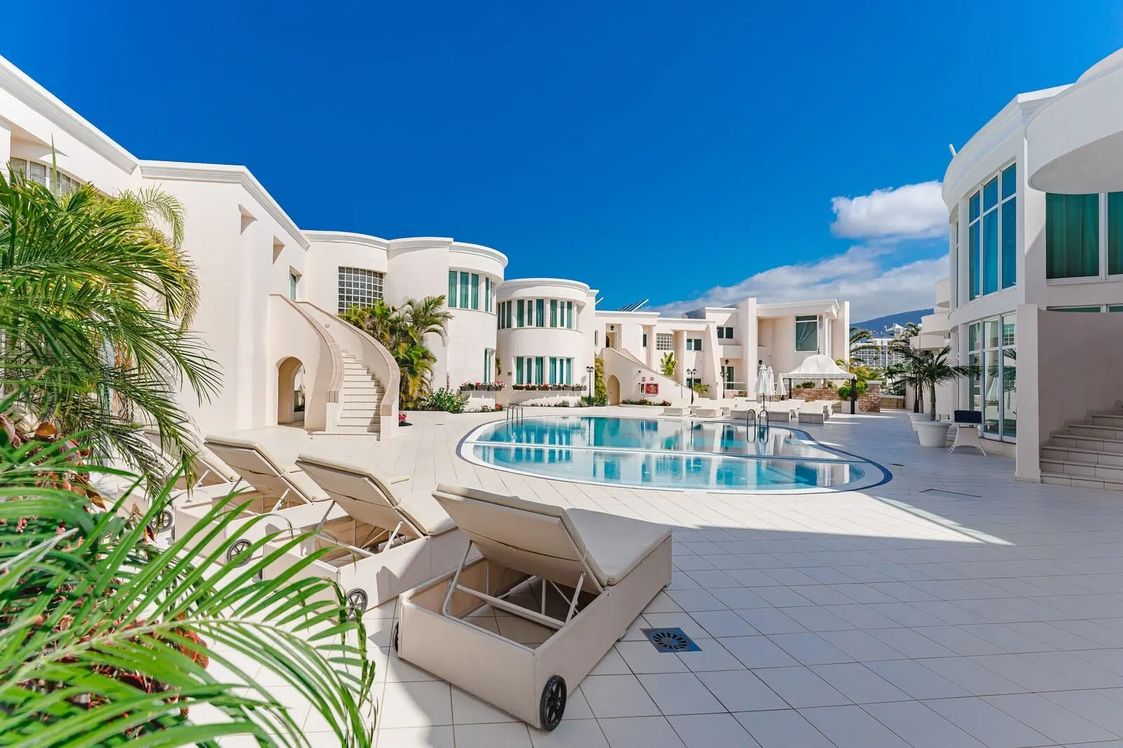 Flamingo Suites Boutique Hotel: A modern resort with a swimming pool, lounge chairs, and a clear blue sky