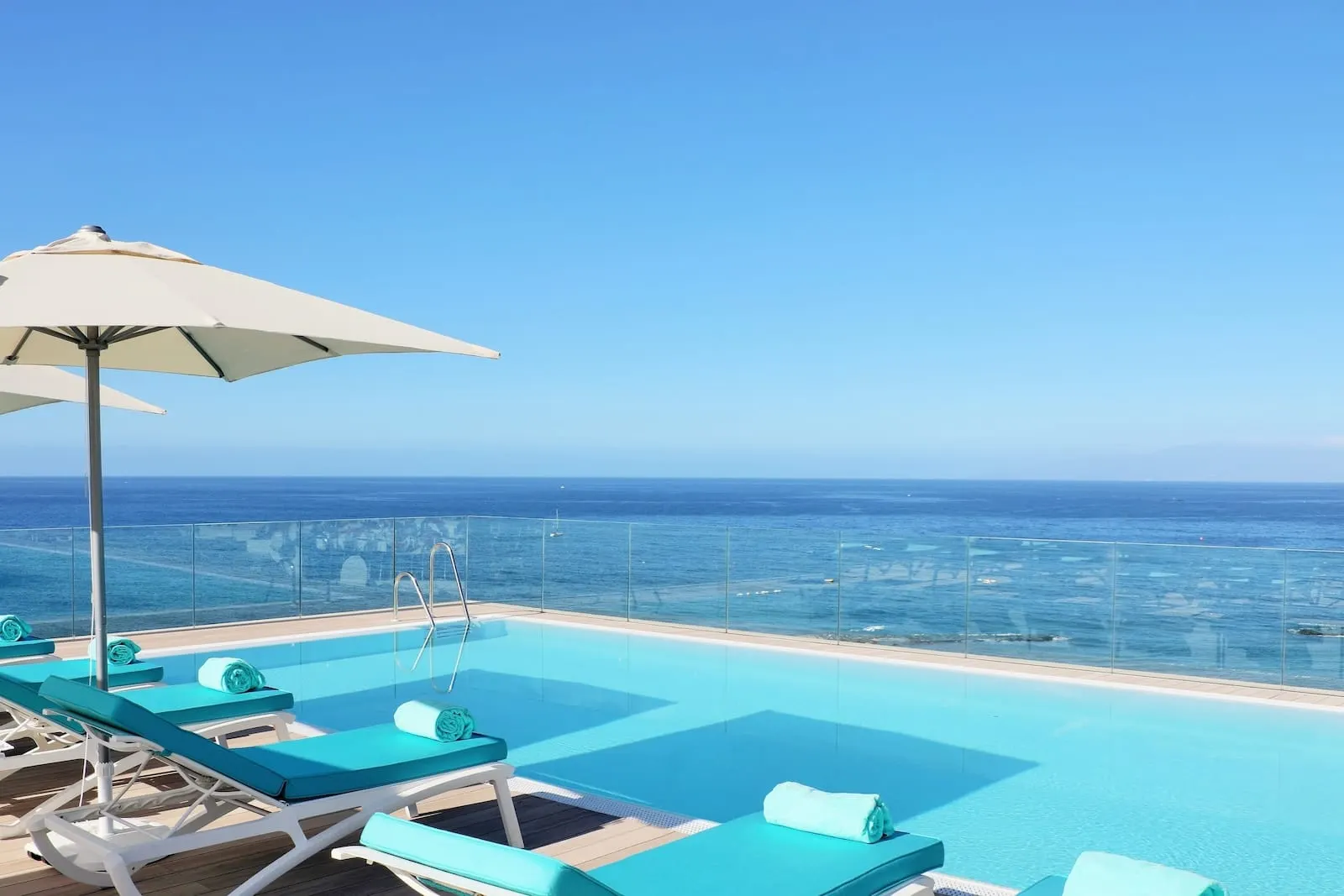 Iberostar Selection Sábila: A poolside area with lounge chairs and an umbrella, overlooking a clear blue sea